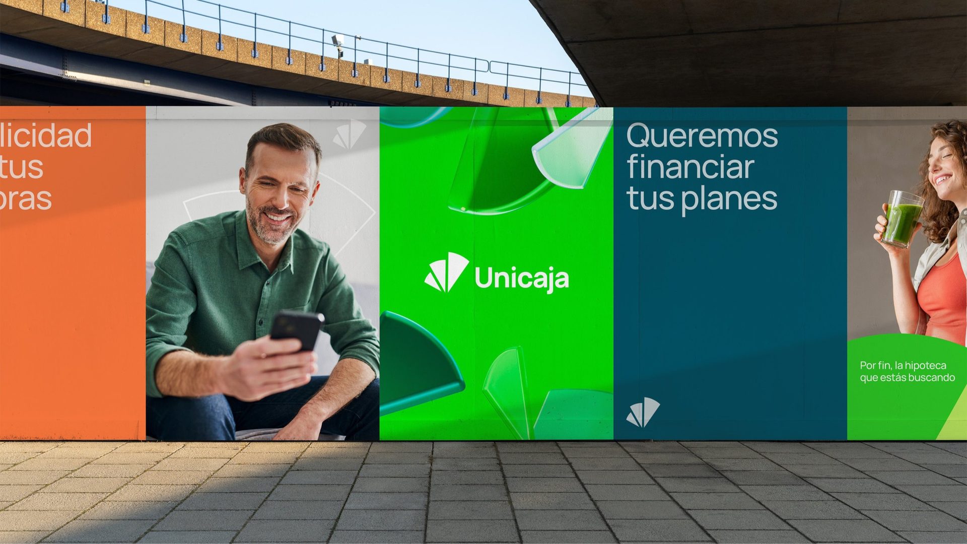 Unicaja hoarding under a bridge with portraits, the logo and Queremos financiar tus planes